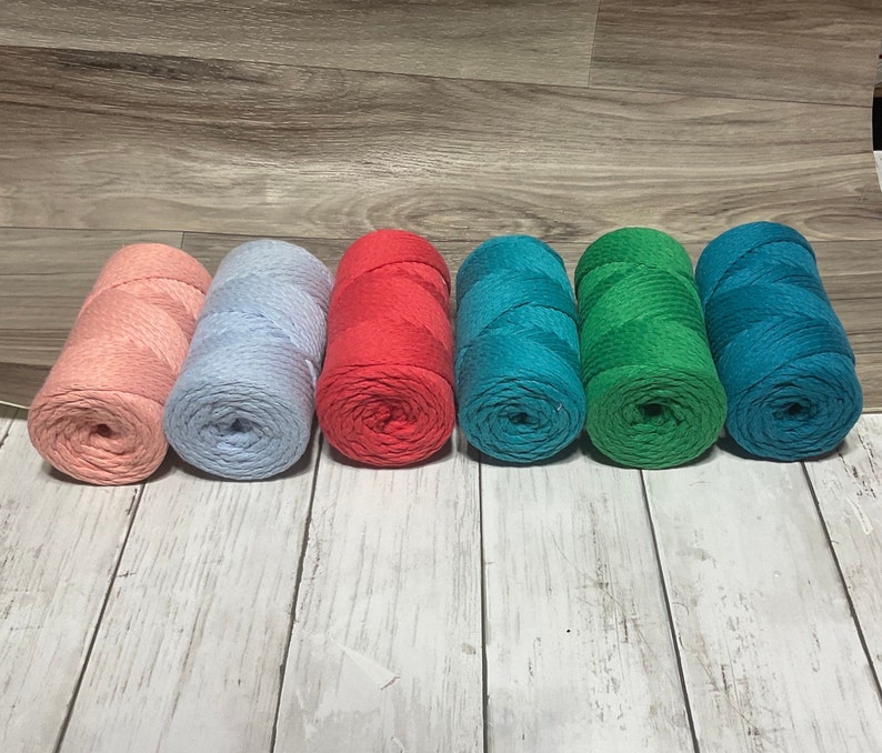 May include: Six spools of cotton rope in various colors. The spools are arranged in a row from left to right: light pink, light blue, red, teal, green, and dark teal.