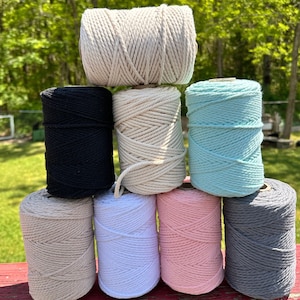 May include: Eight spools of cotton rope in various colors, including natural, black, white, pink, gray, and light blue. The spools are stacked in a pyramid shape.