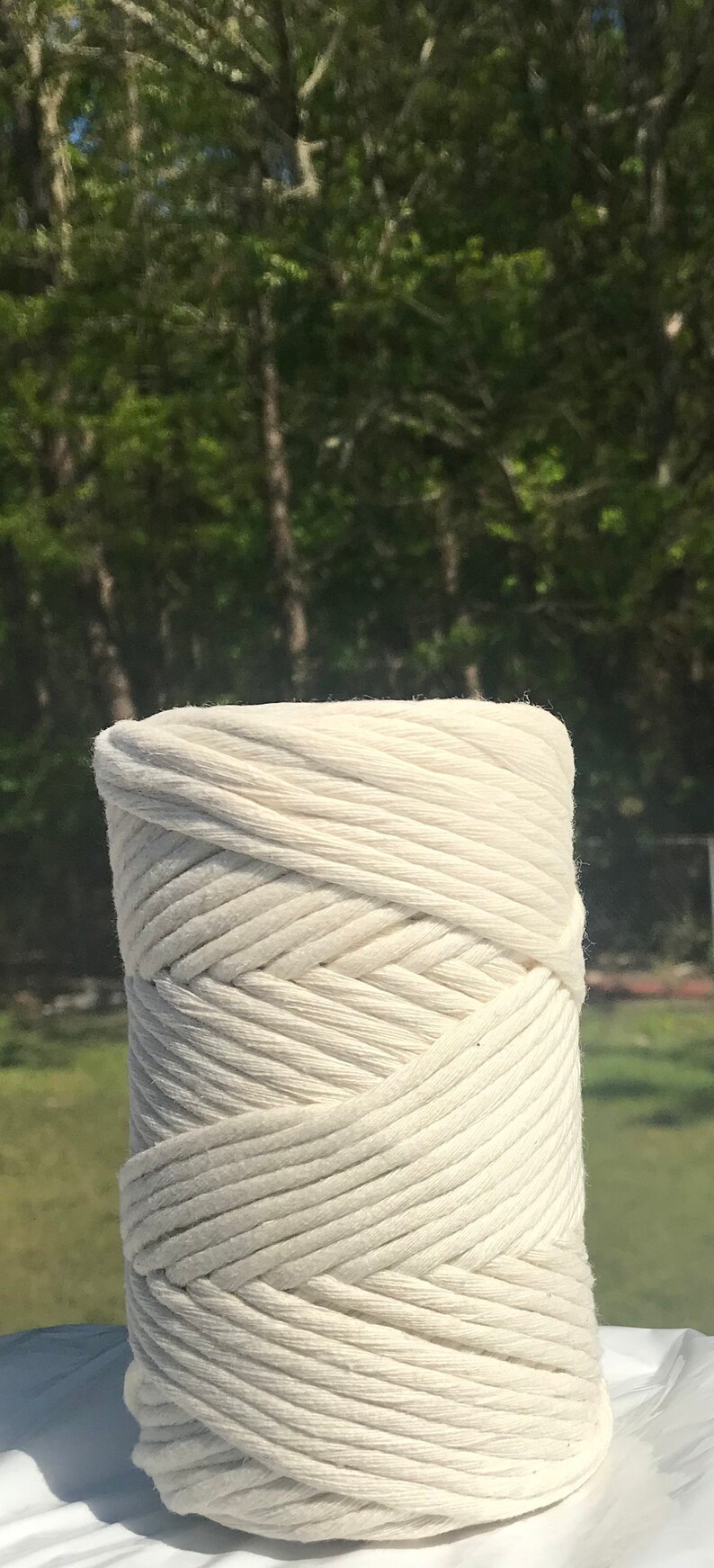 Pode incluir: Um close-up de uma corda de algod&atilde;o branca, enrolada em espiral. A corda &eacute; grossa e texturizada, com um aspecto macio e natural.