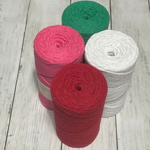 May include: Four spools of twine in red, pink, white, and green. The spools are arranged in a pyramid shape.