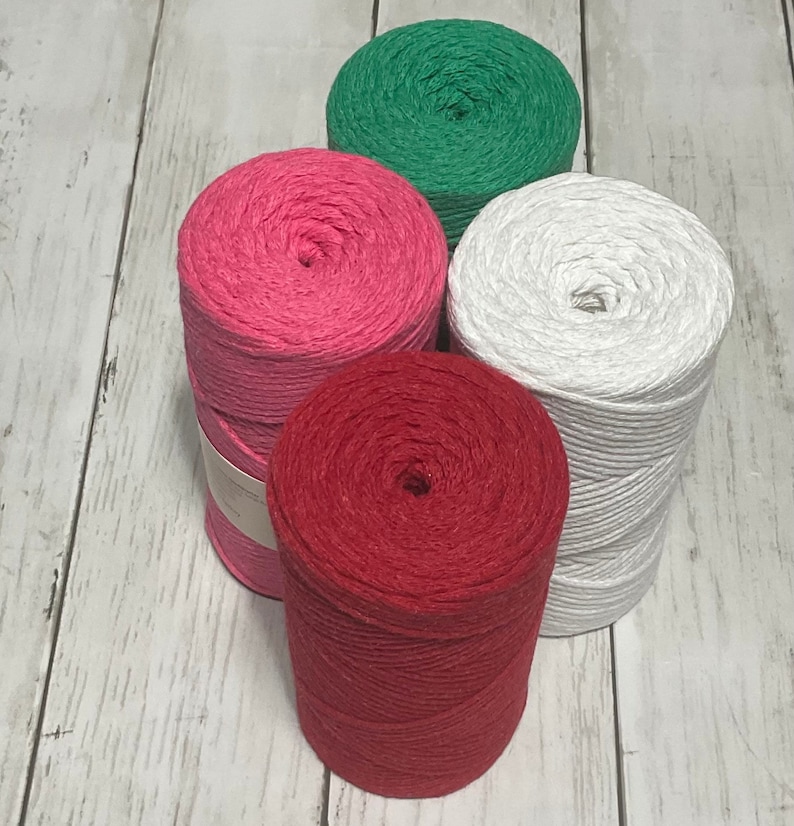 May include: Four spools of twine in red, pink, white, and green. The spools are arranged in a pyramid shape.