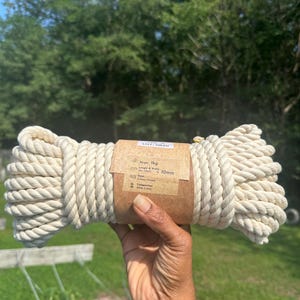 May include: A coil of off-white 10mm cotton rope with a brown paper label stating 1kg weight, 15m length, and 3-times twisted composition. The label also includes the text LOT: 0820 and icons for weight, length, width, twist, and composition.