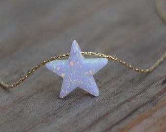 May include: A delicate gold chain necklace with a white opal star pendant. The star has a speckled, iridescent finish.