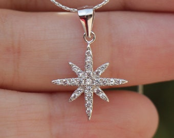 May include: A silver necklace featuring a star-shaped pendant set with small, clear cubic zirconia stones.