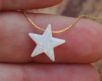 May include: A delicate gold chain necklace with a white opal star pendant.