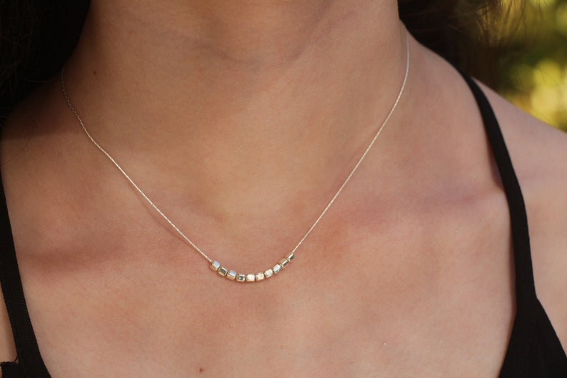 Op de afbeelding: Een zilveren ketting met een rij kleine, vierkante kralen.