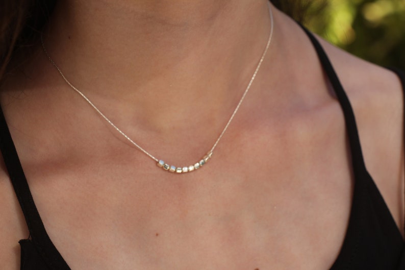Op de afbeelding: Een zilveren ketting met een rij kleine, vierkante kralen.