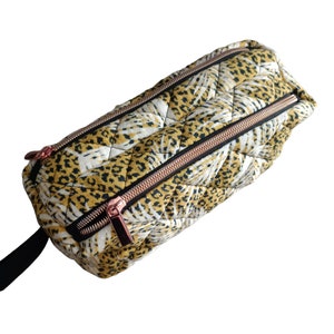 Può includere: Marsupio trapuntato con motivo leopardato giallo, nero e bianco. La borsa presenta due cerniere con finiture in oro rosa e un cinturino nero. La borsa rettangolare ha un motivo a rombi.