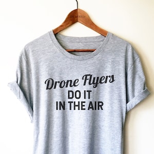 May include: Gray t-shirt with black text that reads "Drone Flyers Do It In The Air".