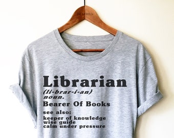 May include: Gray t-shirt with a black graphic that reads "Librarian (li-brar-i-an) noun. Bearer Of Books see also: keeper of knowledge wise guide calm under pressure"