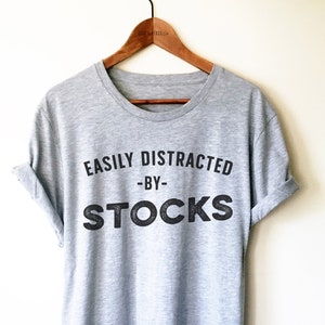 May include: Grey t-shirt with the text "EASILY DISTRACTED -BY- STOCKS" printed on the front.