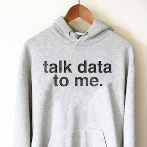 Peut inclure: Un sweat à capuche gris avec le texte "talk data to me." imprimé en noir.
