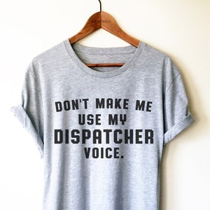 May include: Gray t-shirt with black text that reads "Don't make me use my dispatcher voice."