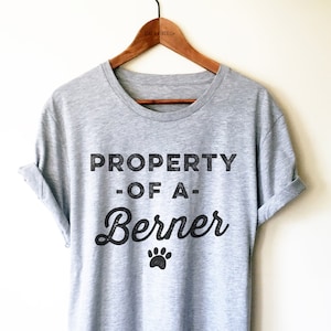 May include: Gray t-shirt with black text that reads "PROPERTY OF A Berner" with a paw print below the text.