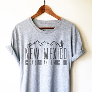 May include: Gray t-shirt with a graphic of mountains and cacti with the text "New Mexico is calling and I must go."