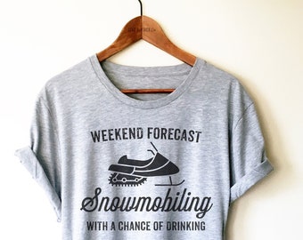 Puede incluir: Camiseta gris con un gráfico negro de una moto de nieve y el texto "Pronóstico del fin de semana Esquí de fondo con una posibilidad de beber."