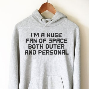 May include: A gray hooded sweatshirt with the text "I'm a huge fan of space both outer and personal" printed on the front.
