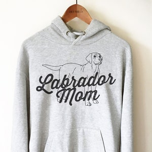 May include: Grey hooded sweatshirt with a black outline of a Labrador Retriever and the text "Labrador Mom" in a black script font.