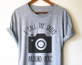 May include: A heather grey t-shirt with a black camera graphic and the text "I call the shots around here".