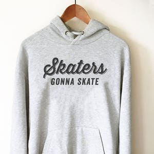 May include: A gray hooded sweatshirt with the text "Skater's Gonna Skate" in black lettering.