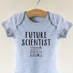 Op de afbeelding: Een grijze baby romper met de tekst "FUTURE SCIENTIST" in zwarte letters. Onder de tekst staat een zwart-witte illustratie van reageerbuizen in een rek.