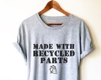 May include: A gray t-shirt with the text "MADE WITH RECYCLED PARTS" in black lettering. A small black heart graphic is below the text.
