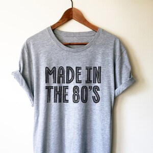 May include: A heather grey t-shirt with black text that reads "Made in the 80's".