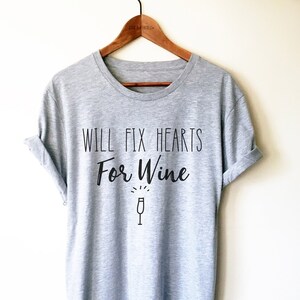 May include: Gray t-shirt with the text "Will Fix Hearts For Wine" and a wine glass icon.