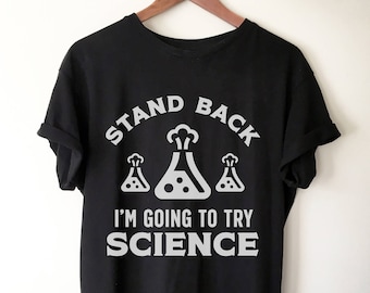 May include: Black t-shirt with white text that reads "Stand Back I'm Going To Try Science". The text is surrounded by three cartoon beakers with bubbling liquid.