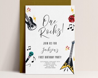 Può includere: Un biglietto d'invito bianco con una busta dorata. La carta presenta il testo "One Rocks!" e "Join us for Jackson's First Birthday Party". Include illustrazioni di una chitarra, un microfono, note musicali e una rosa.