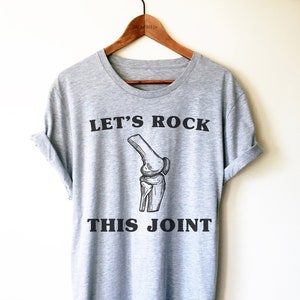 May include: Gray t-shirt with a black graphic of a knee bone and the text "Let's Rock This Joint".