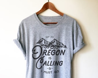 May include: Grey t-shirt with a black graphic print of mountains and the text "Oregon is Calling -& - I Must Go".