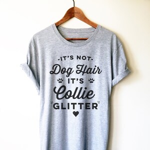 Puede incluir: Camiseta gris con texto negro que dice "No es pelo de perro, es brillo de Collie" con un peque&ntilde;o coraz&oacute;n negro debajo del texto.