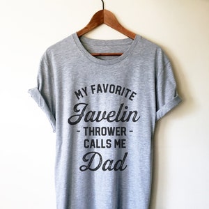 May include: Grey t-shirt with the text "My Favourite Javelin Thrower Calls Me Dad" printed on it.