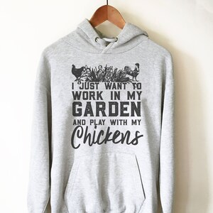 May include: A gray hooded sweatshirt with the text "I just want to work in my garden and play with my chickens" printed on the front.