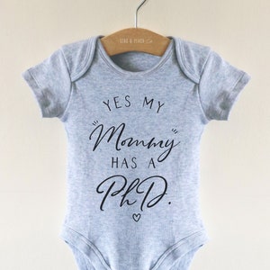 May include: A gray baby onesie with the text "Yes my "Mommy" has a PhD." in black lettering.