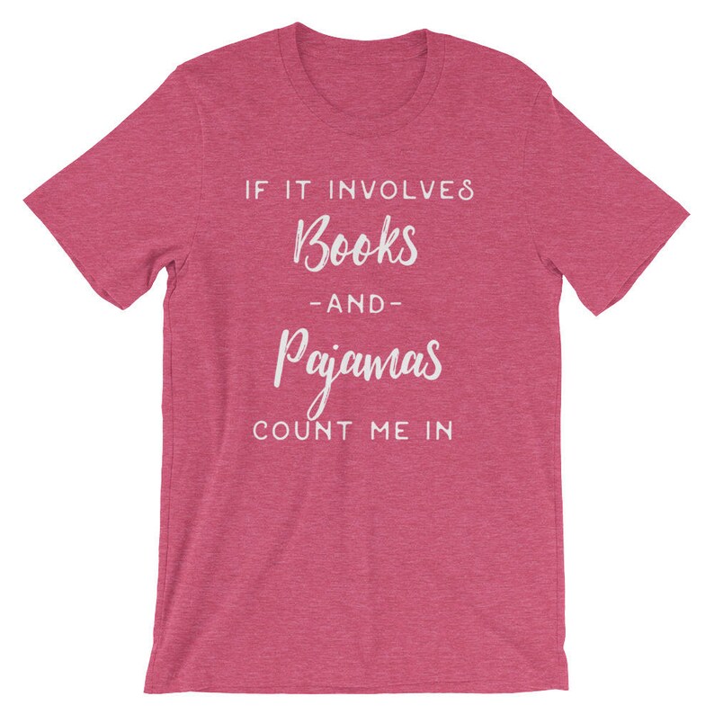 May include: A pink heather t-shirt with the text "If it involves books -and- pajamas count me in" in white.