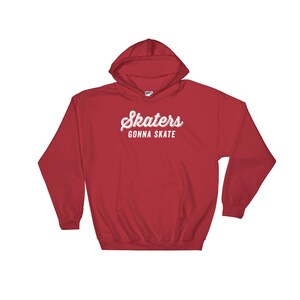 May include: Red hooded sweatshirt with the text "Skaters Gonna Skate" in white cursive lettering.