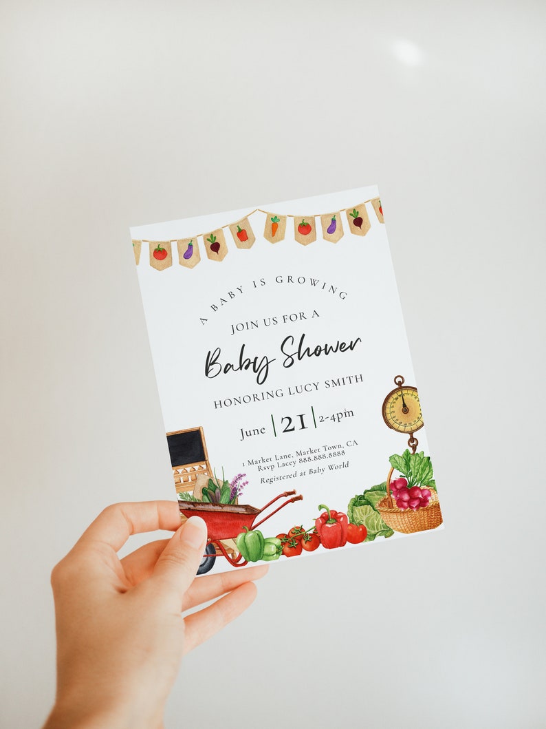 May include: A white baby shower invitation with a watercolor illustration of vegetables and a wheelbarrow. The text reads "A baby is growing. Join us for a baby shower honoring Lucy Smith. June 21, 2-4pm. Market Lane, Market Town, CA. Rsvp Lacey 888.888.8888. Registered at Baby World."