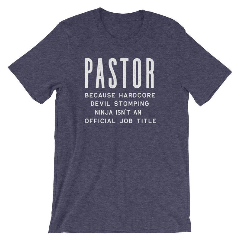 May include: Navy blue t-shirt with white text that reads "PASTOR because hardcore devil stomping ninja isn't an official job title".