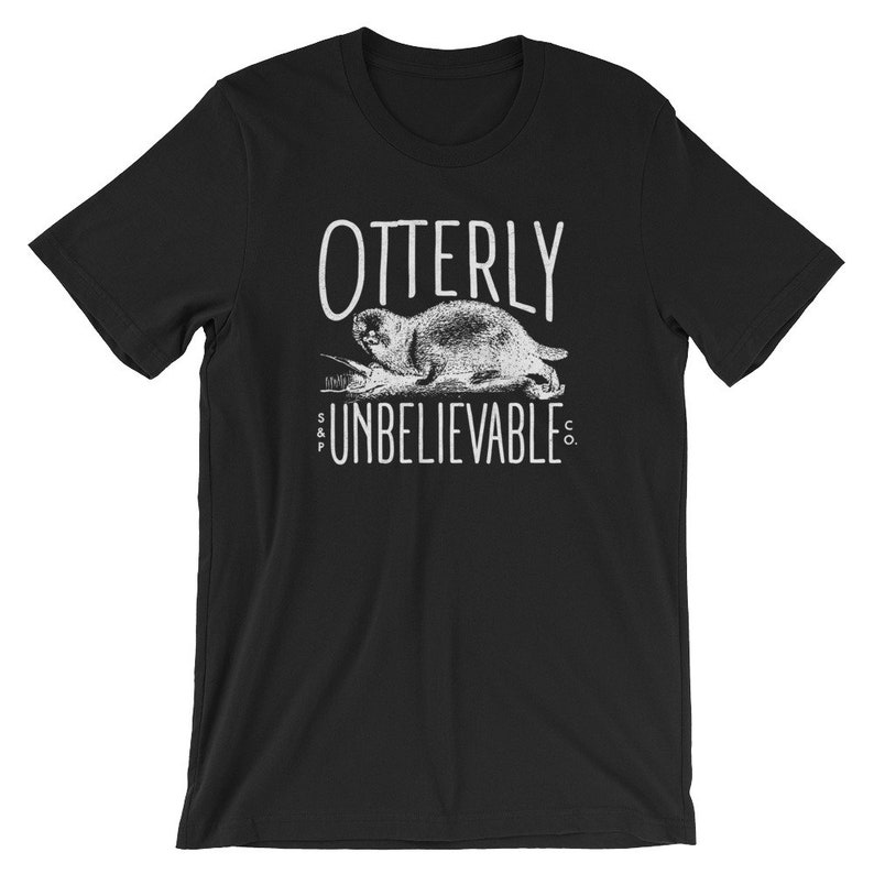 Puede incluir: Camiseta negra con un gr&aacute;fico blanco de una nutria y el texto "OTTERLY UNBELIEVABLE CO."