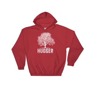 Puede incluir: Sudadera con capucha roja con un gr&aacute;fico de &aacute;rbol blanco y la palabra "HUGGER" impresa debajo del &aacute;rbol.