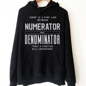 Puede incluir: Sudadera con capucha negra con un estampado gr&aacute;fico blanco que dice "There is a fine line between numerator and denominator *only a fraction will understand".