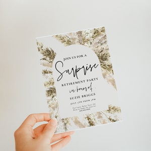 May include: A white card with a watercolor background of beige and green foliage. The text on the card reads "Join us for a Surprise Retirement Party in honor of Suzie Briggs July 5th from 7PM Fun Lane, Relax Town, CA RSVP to Sadie by June 1st 555.555.5558"