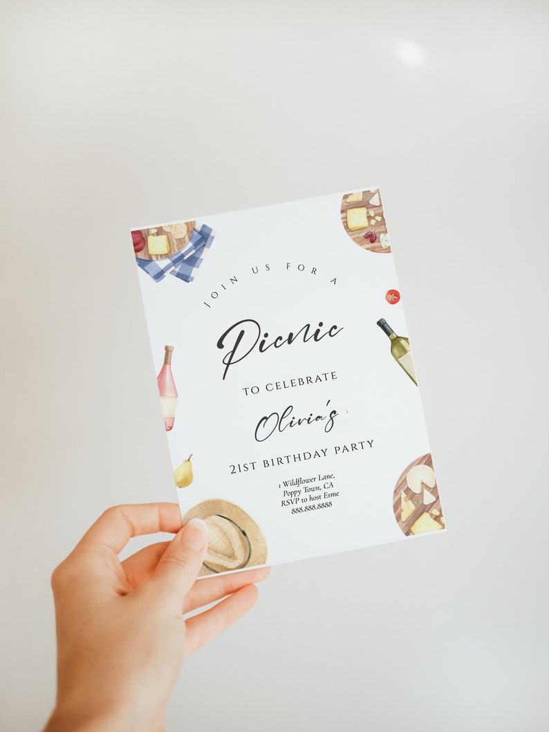 May include: A white invitation card with a watercolor illustration of a picnic basket with food and wine. The text on the card reads "Join us for a Picnic to celebrate Olivia's 21st Birthday Party". The invitation includes the address and RSVP information.