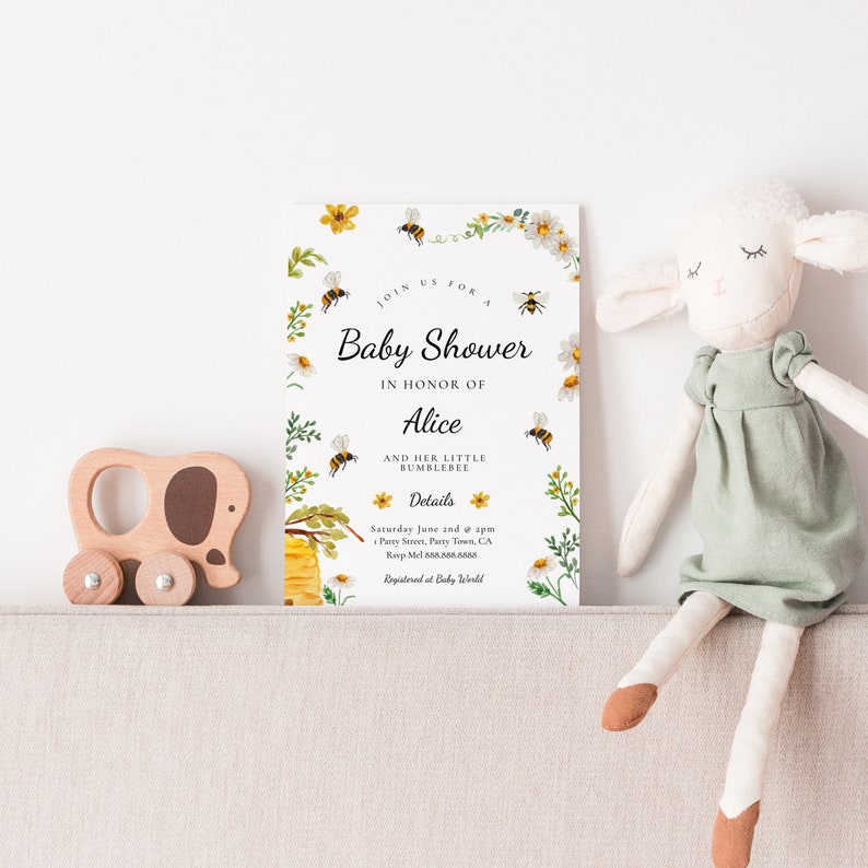 May include: A white baby shower invitation with a bee and honeycomb design. The invitation says "Join us for a Baby Shower in honor of Alice and her little bumblebee".