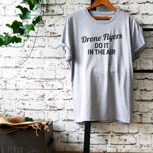 May include: Gray t-shirt with the text "Drone Flyers Do It In The Air" printed in black.