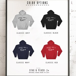 Puede incluir: Un dise&ntilde;o gr&aacute;fico para una sudadera con capucha con el texto "Happiest When It Rains" en una fuente de escritura blanca. La sudadera con capucha se muestra en cinco colores diferentes: gris cl&aacute;sico, negro cl&aacute;sico, azul marino cl&aacute;sico, rojo cl&aacute;sico y blanco cl&aacute;sico.