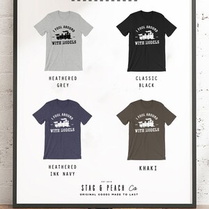 May include: A graphic t-shirt design featuring a train with the text "I fool around with models". The shirt is available in five colors: heather grey, classic black, heather ink navy, khaki, and white.