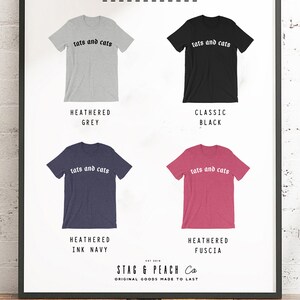 May include: Four t-shirt mockups showing different colour options. The t-shirts are all crew neck and short-sleeved. The text "tats and cats" is printed in black on the front of each shirt. The colour options are: Heathered Grey, Classic Black, Heathered Ink Navy, and Heathered Fuscia.